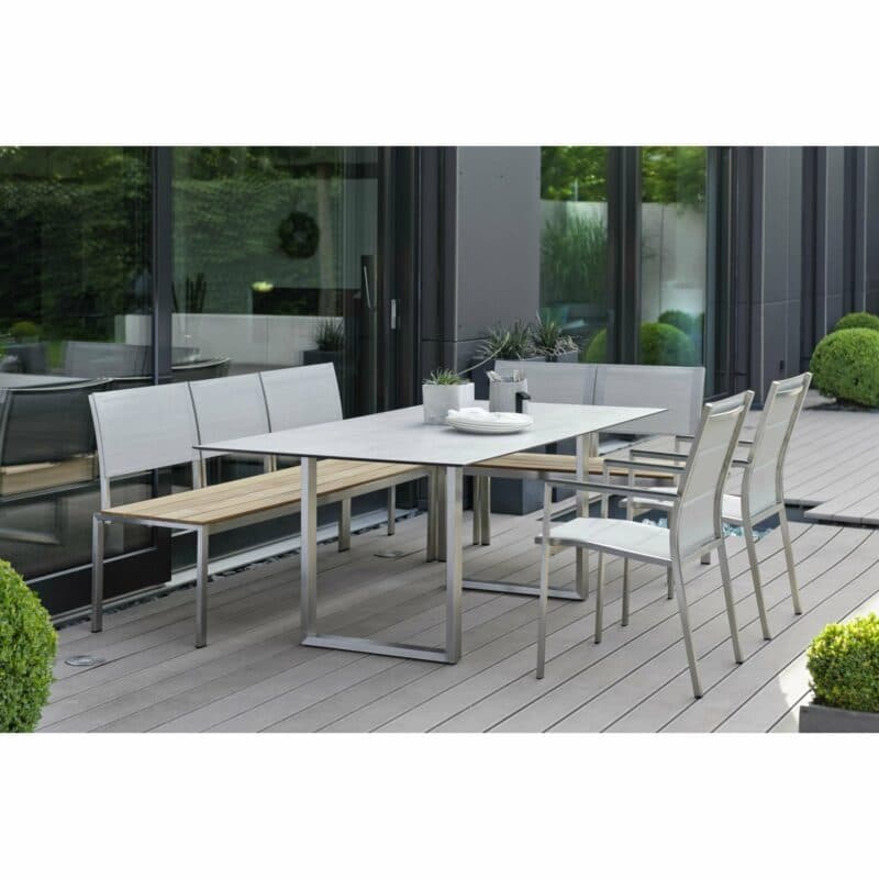 Stern Stapelsessel "Cardiff", Gestell Edelstahl, Textilgewebe silber gepolstert, Armlehnen Alu anthrazit, Bank "Arima" mit Teak, Kufentisch Edelstahl, Platte HPL Zement hell