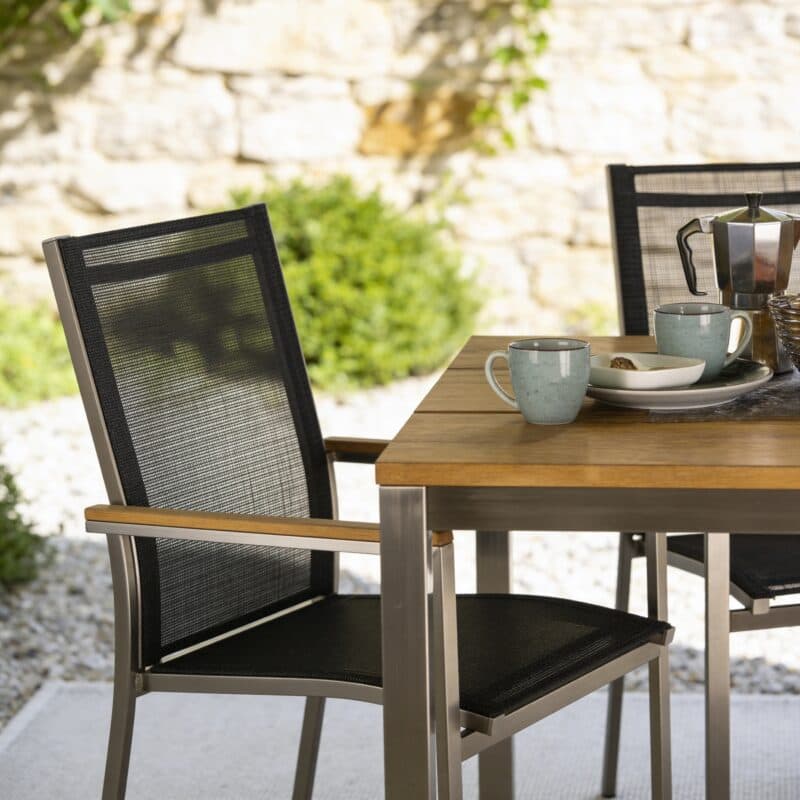 Liadomo "Motta" Stapelstuhl, Edelstahl gebürstet, Textilgewebe anthrazit, Armlehnen Teak (Bild KI-generiert)