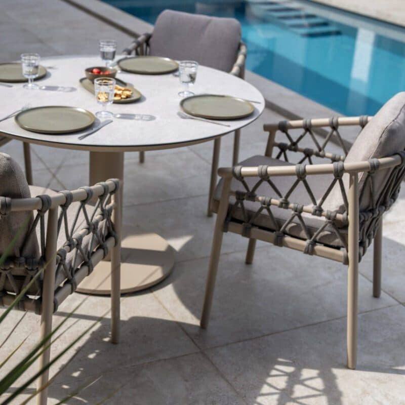 Runder Tisch mit Rope-Sesseln stehen neben einem blauen Pool