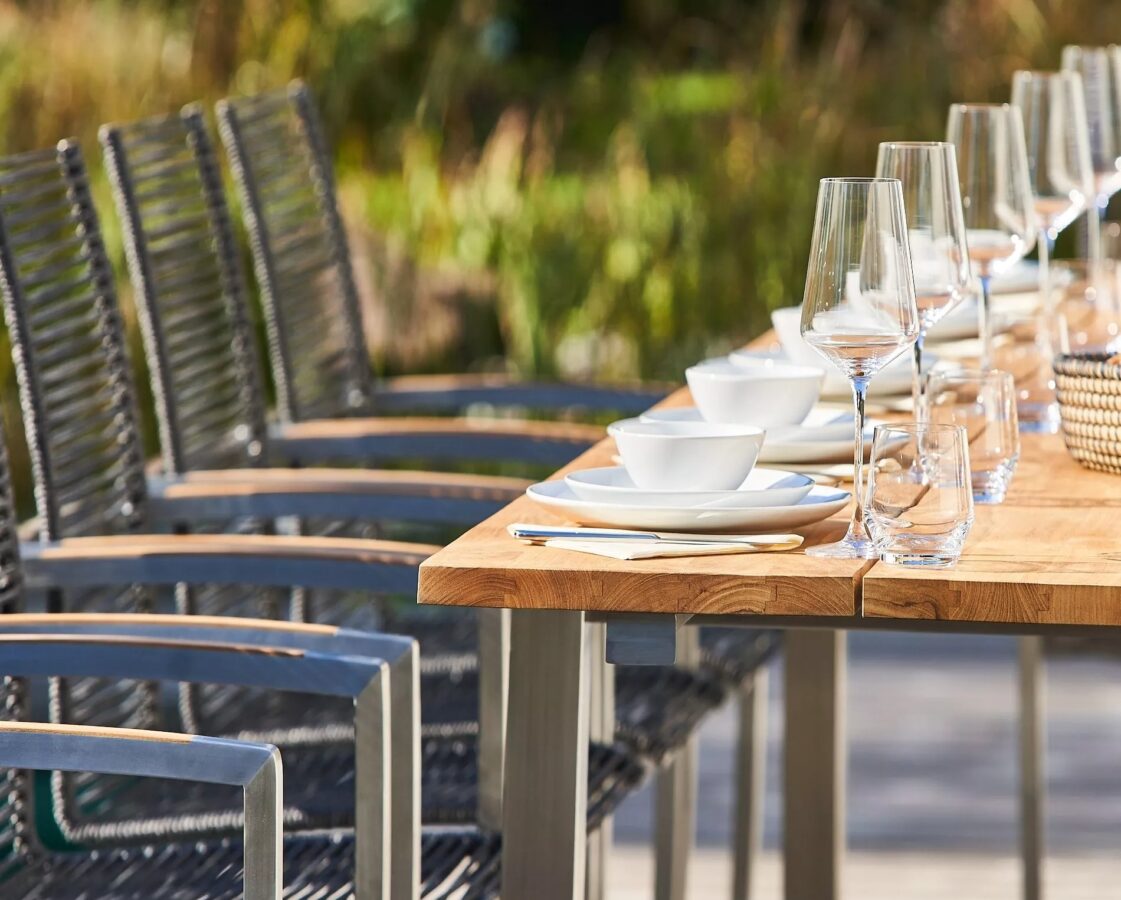 Ein mit Tellern und Weingläsern gedeckter Teakholztisch