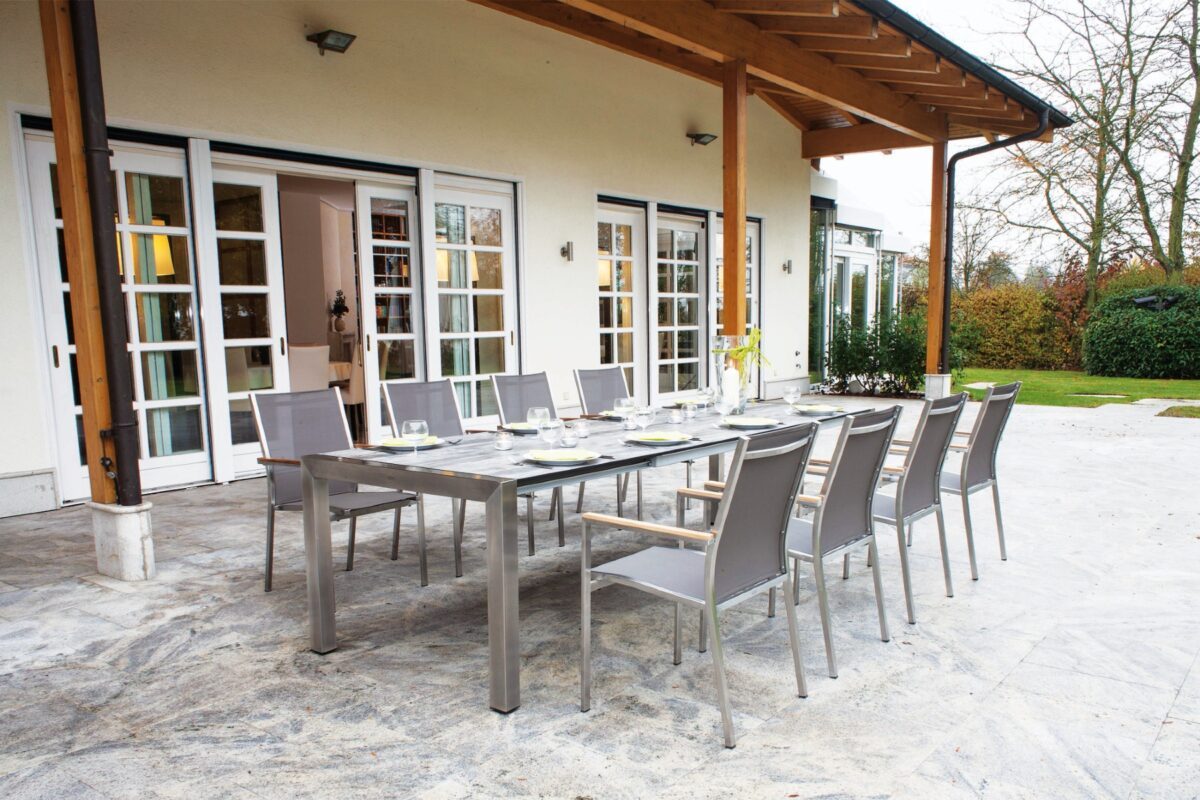Große Gartenmöbel-Essgruppe aus Edelstahl vor einem eleganten Landhaus