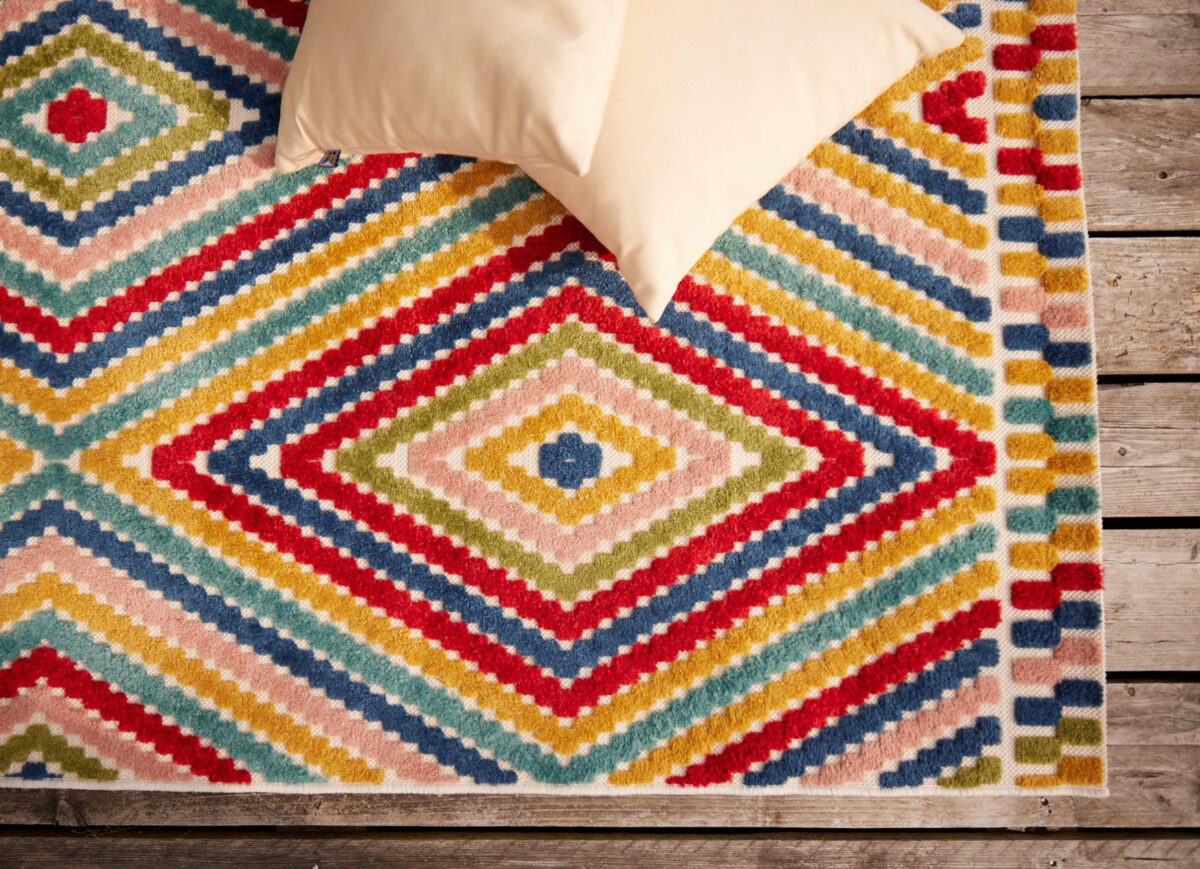 Bunter Outdoor-Teppich und Kissen auf Terrassenboden