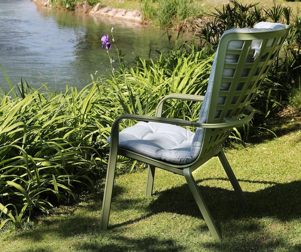 Hoher Loungesessel steht auf einer Wiese am See
