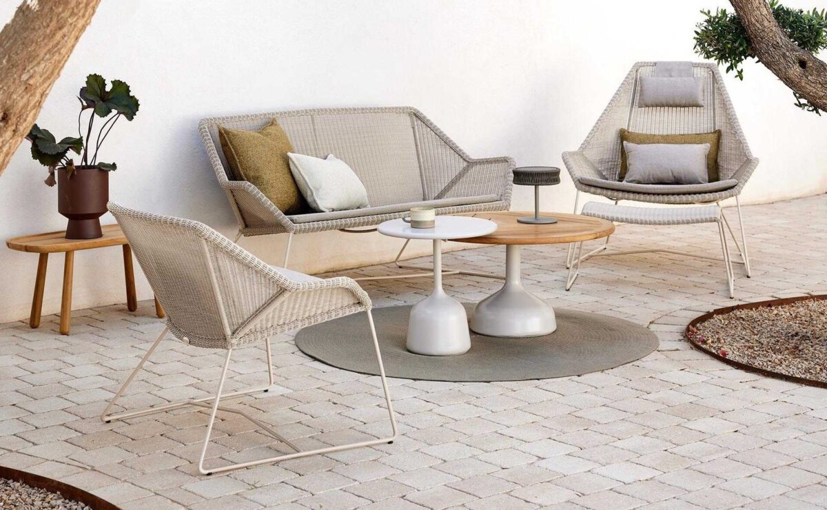 Eine Gruppe von Loungemöbeln aus hellem Polyrattan auf einer modernen Terrasse
