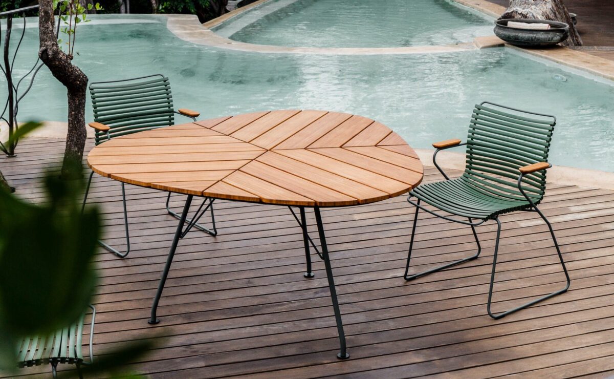 Tisch in Blattform mit schlanken Stühlen auf einer Terrasse mit großem Pool
