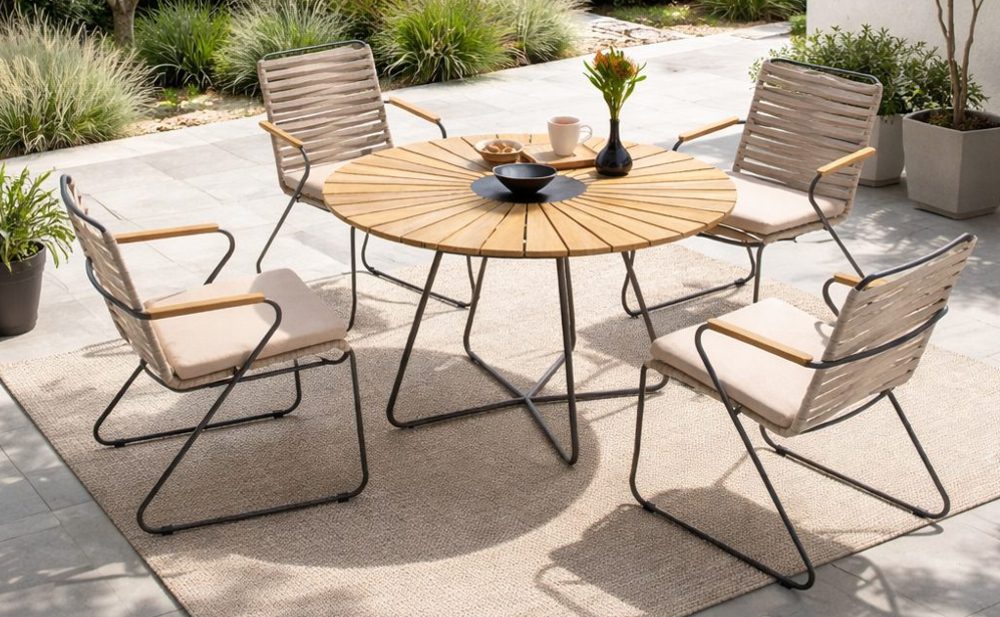 Runder Tisch mit schlanken Rope-Stühlen auf einer Terrasse mit hellem Outdoor-Teppich